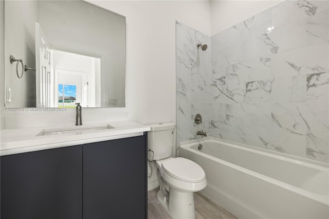 full bathroom featuring hardwood / wood-style flooring, toilet, vanity, and tiled shower / bath