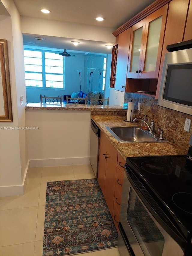 kitchen featuring light tile patterned floors, appliances with stainless steel finishes, sink, and light stone countertops