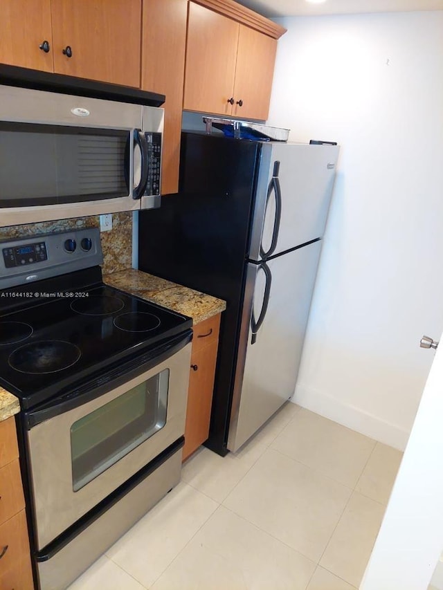 kitchen featuring stainless steel appliances, light tile patterned floors, and light stone countertops