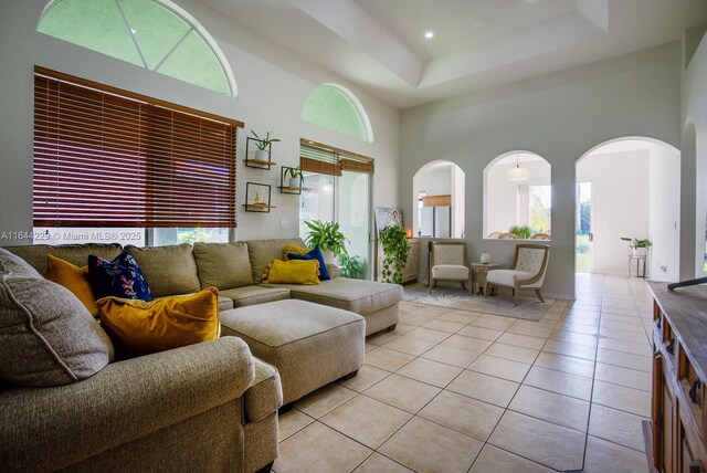 tiled living room with a high ceiling and a raised ceiling