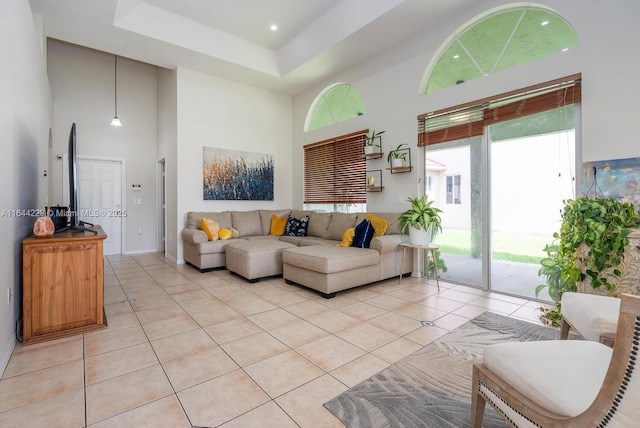 living area featuring a raised ceiling, light tile patterned flooring, and a towering ceiling