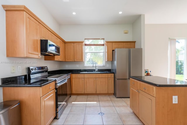 kitchen featuring appliances with stainless steel finishes, light tile patterned floors, sink, and dark stone counters