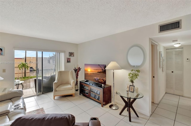 living area with light tile patterned floors, a textured ceiling, visible vents, and baseboards