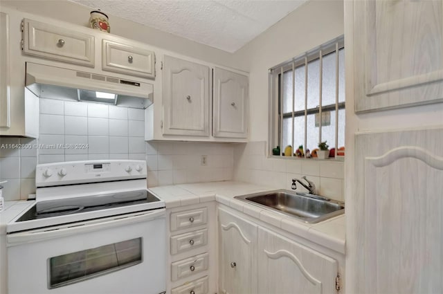 kitchen featuring sink, white electric range oven, a textured ceiling, and backsplash