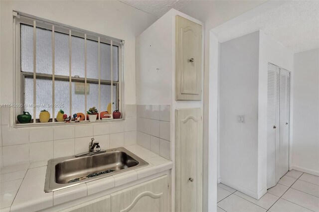 kitchen featuring sink, tile countertops, light tile patterned floors, and tasteful backsplash