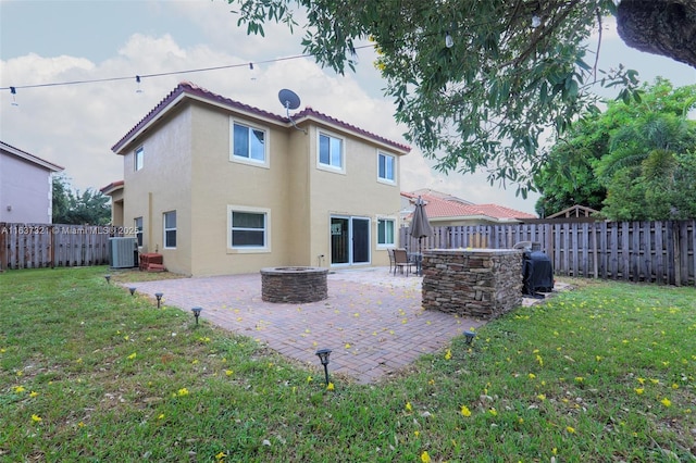 rear view of house featuring a fire pit, a patio area, central air condition unit, and a yard