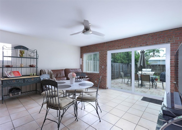 tiled dining room featuring ceiling fan and brick wall