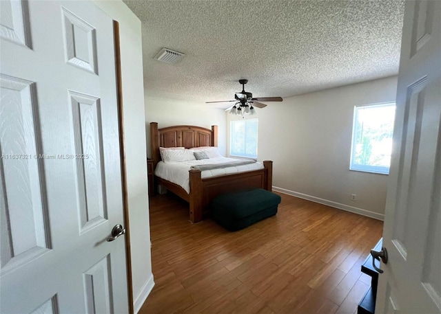 bedroom with wood-type flooring, a textured ceiling, and ceiling fan