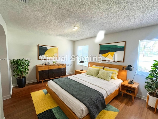 bedroom with multiple windows, wood-type flooring, and a textured ceiling