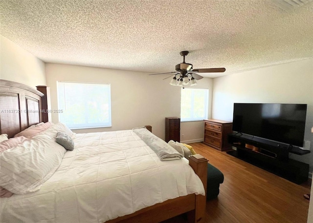 bedroom with ceiling fan, hardwood / wood-style floors, and a textured ceiling