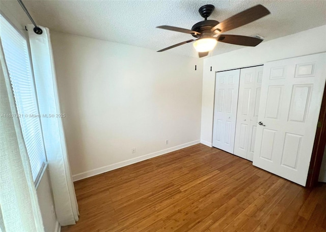 unfurnished bedroom featuring a textured ceiling, ceiling fan, dark wood-type flooring, and a closet