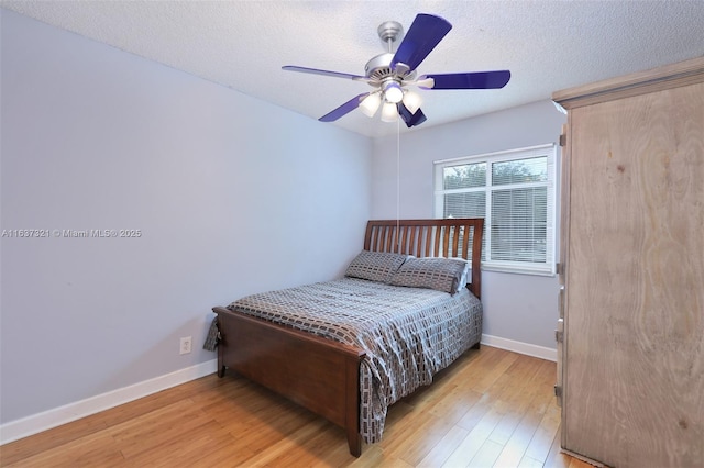 bedroom featuring ceiling fan, light hardwood / wood-style flooring, and a textured ceiling