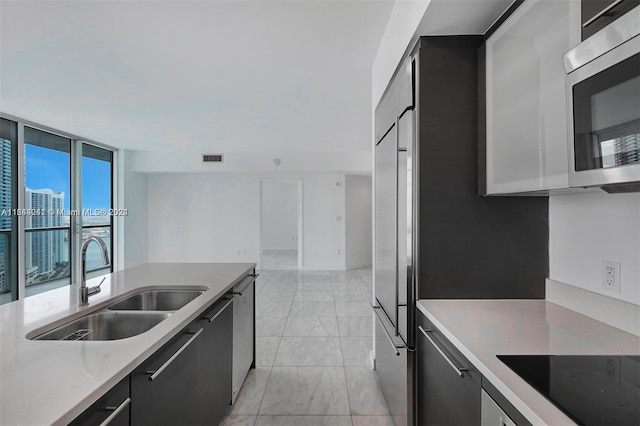 kitchen featuring light tile patterned floors, appliances with stainless steel finishes, sink, and a wall of windows