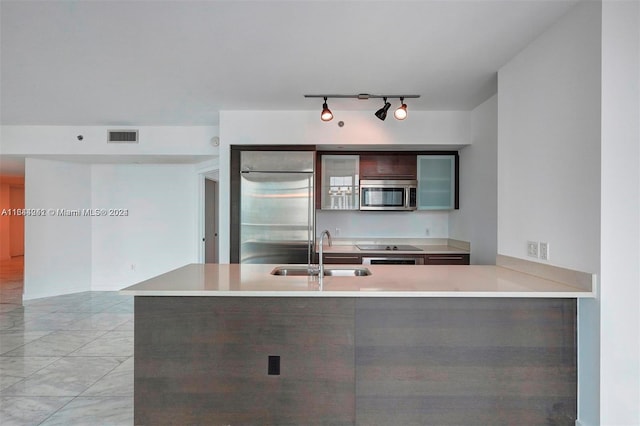 kitchen featuring appliances with stainless steel finishes, rail lighting, sink, light tile patterned floors, and kitchen peninsula