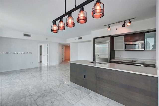 kitchen featuring sink, hanging light fixtures, dark brown cabinets, light tile patterned floors, and stainless steel appliances