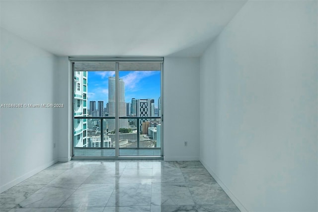 tiled empty room featuring a wall of windows