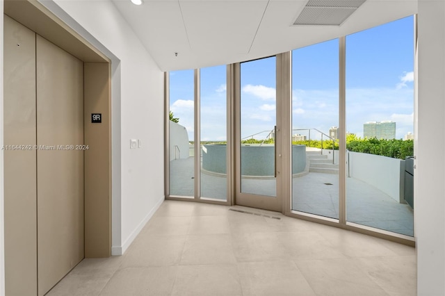 interior space with light tile patterned flooring, elevator, and floor to ceiling windows