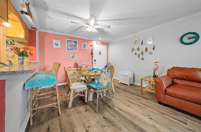 dining area with a textured ceiling, ceiling fan, hardwood / wood-style floors, and crown molding