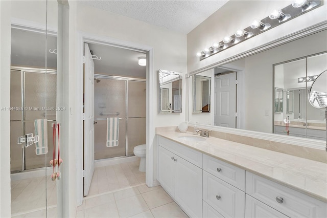 bathroom with a shower with shower door, a textured ceiling, tile patterned flooring, vanity, and toilet