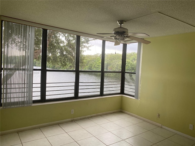 tiled spare room featuring a wealth of natural light, ceiling fan, and a textured ceiling