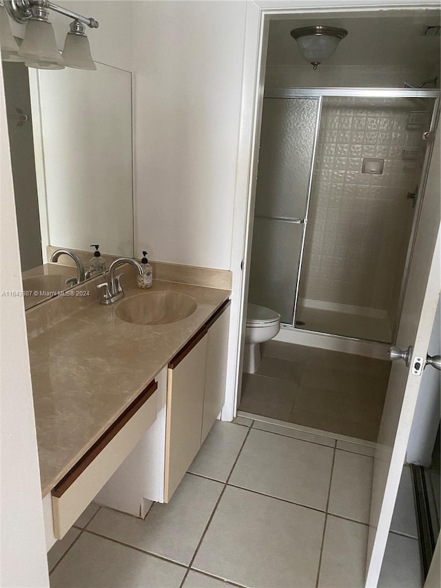 bathroom featuring tile patterned flooring, toilet, vanity, and walk in shower