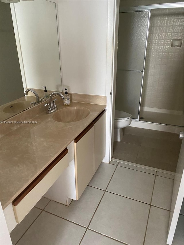 bathroom with an enclosed shower, toilet, vanity, and tile patterned floors