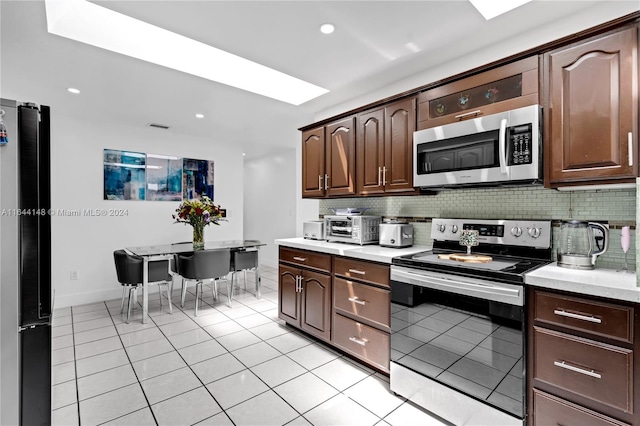 kitchen featuring light tile patterned floors, tasteful backsplash, stainless steel appliances, and dark brown cabinets