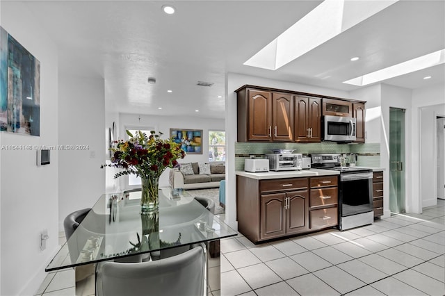 kitchen with appliances with stainless steel finishes, light tile patterned floors, and a skylight