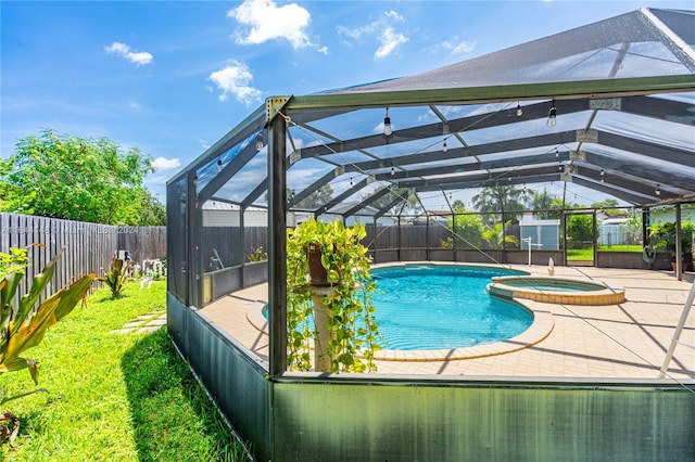 view of pool with glass enclosure, an in ground hot tub, and a patio area