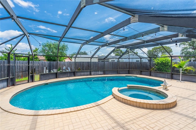 view of swimming pool with glass enclosure, a patio area, and an in ground hot tub