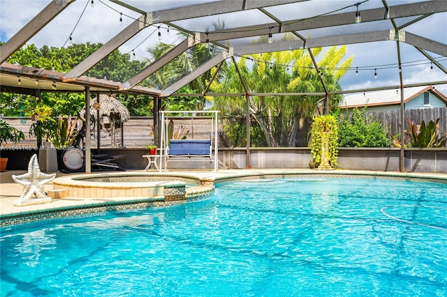 view of swimming pool with an in ground hot tub and a lanai