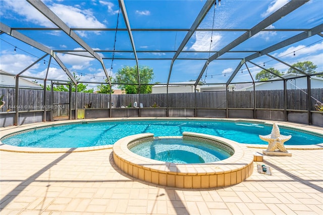 view of swimming pool with an in ground hot tub, glass enclosure, and a patio