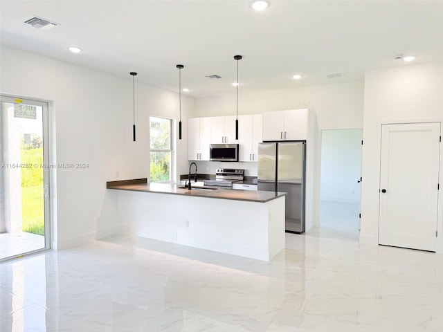 kitchen with pendant lighting, white cabinetry, appliances with stainless steel finishes, and sink