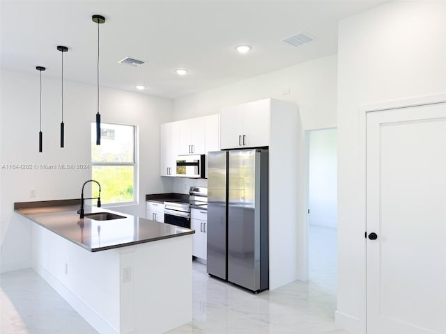 kitchen with white cabinetry, sink, kitchen peninsula, appliances with stainless steel finishes, and decorative light fixtures