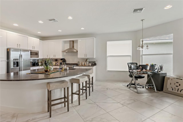 kitchen featuring a kitchen bar, visible vents, dark countertops, stainless steel appliances, and wall chimney exhaust hood