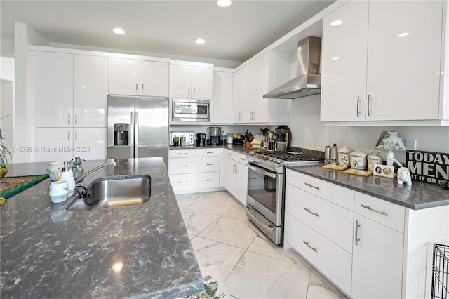 kitchen featuring a sink, stainless steel appliances, wall chimney exhaust hood, and white cabinets