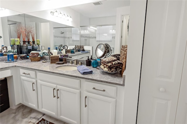 full bathroom with vanity, a shower stall, and visible vents