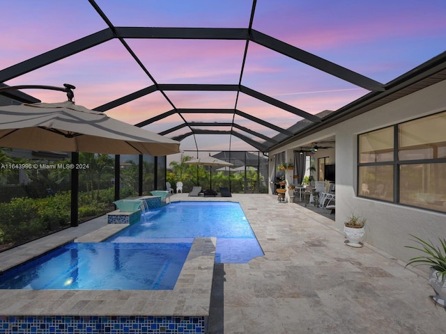 view of swimming pool featuring ceiling fan, glass enclosure, pool water feature, a patio area, and an in ground hot tub