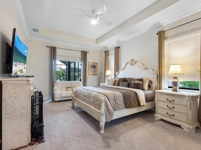 bedroom with light carpet, ornamental molding, a tray ceiling, and ceiling fan