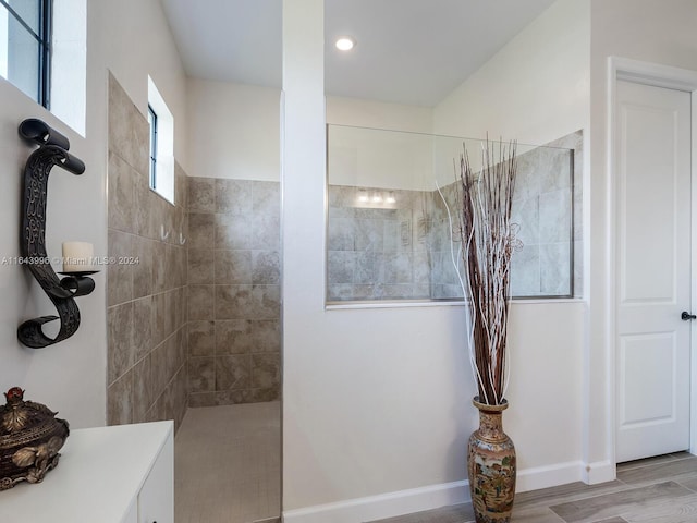 bathroom with hardwood / wood-style flooring and tiled shower