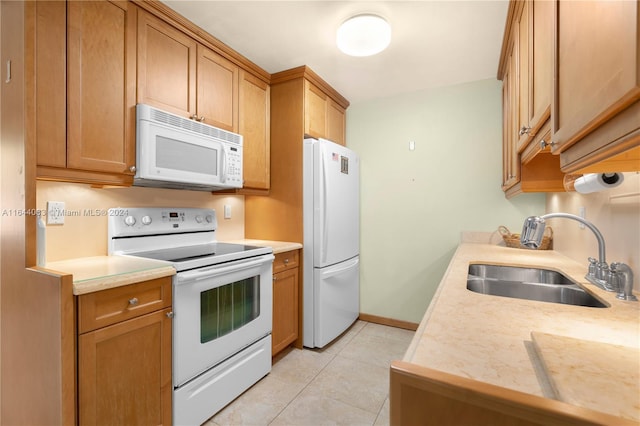 kitchen with light tile patterned floors, white appliances, and sink