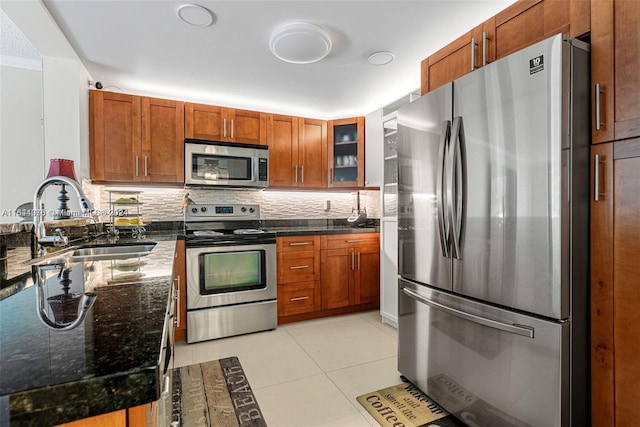 kitchen featuring light tile patterned flooring, sink, dark stone countertops, appliances with stainless steel finishes, and decorative backsplash