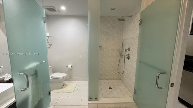 bathroom with tile patterned flooring, toilet, and a shower with door