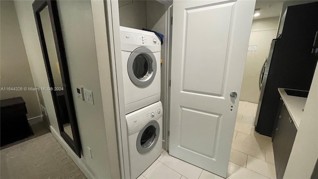 laundry room with light tile patterned flooring and stacked washer and clothes dryer