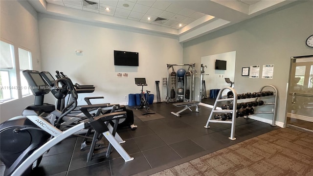 exercise room with a tray ceiling and a high ceiling