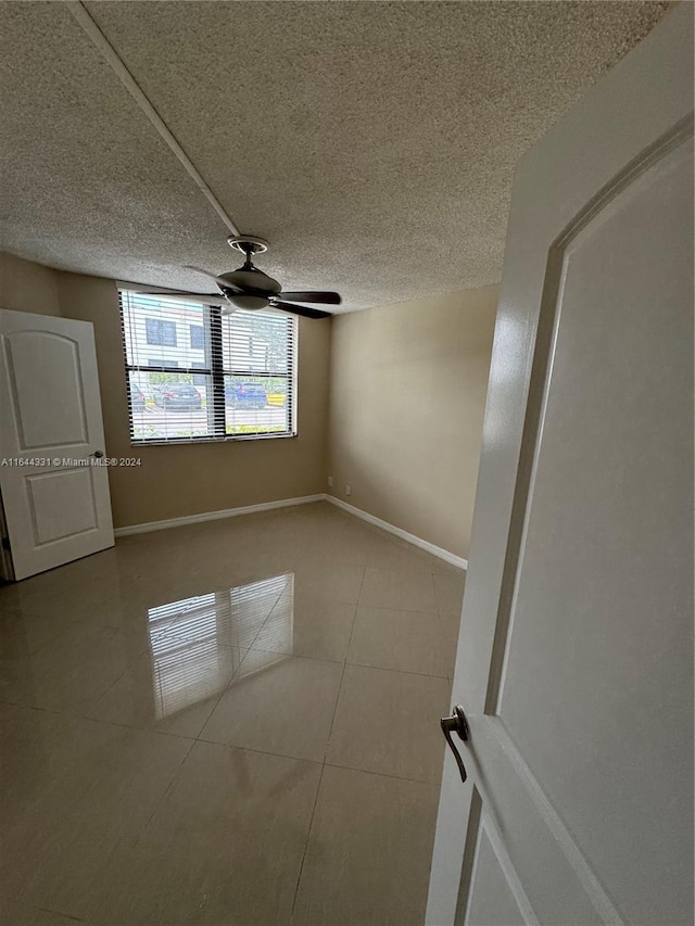 unfurnished room with a textured ceiling, ceiling fan, and tile patterned floors