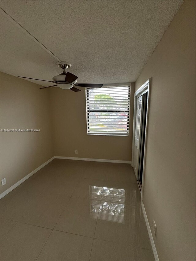 tiled spare room featuring a textured ceiling and ceiling fan