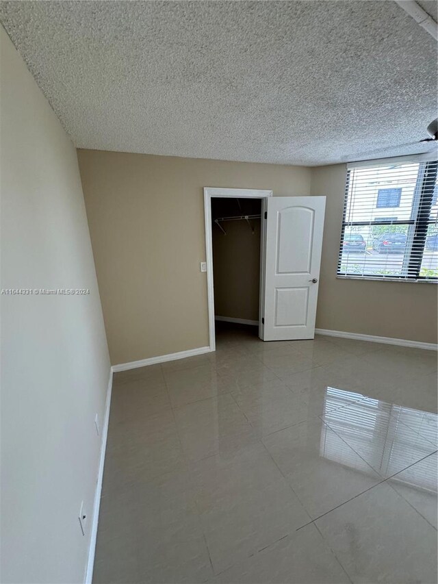 tiled spare room with a textured ceiling