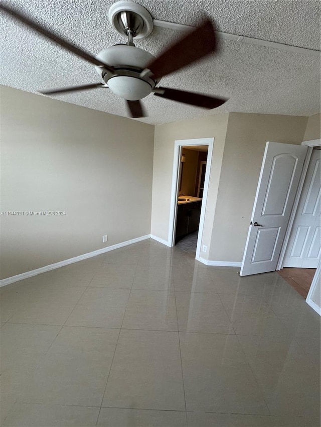 unfurnished room featuring baseboards, a textured ceiling, ceiling fan, and tile patterned flooring