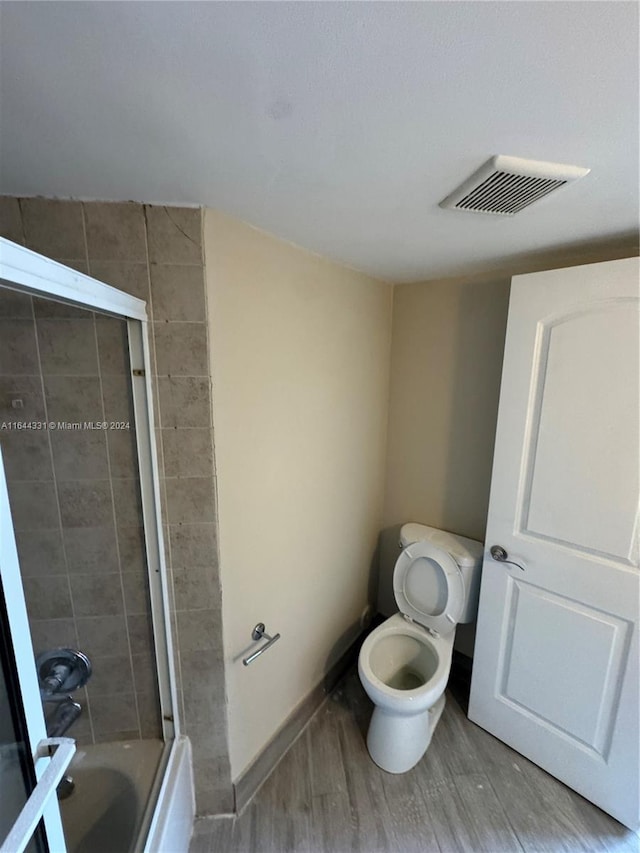 bathroom with visible vents, toilet, wood finished floors, baseboards, and shower / bathtub combination